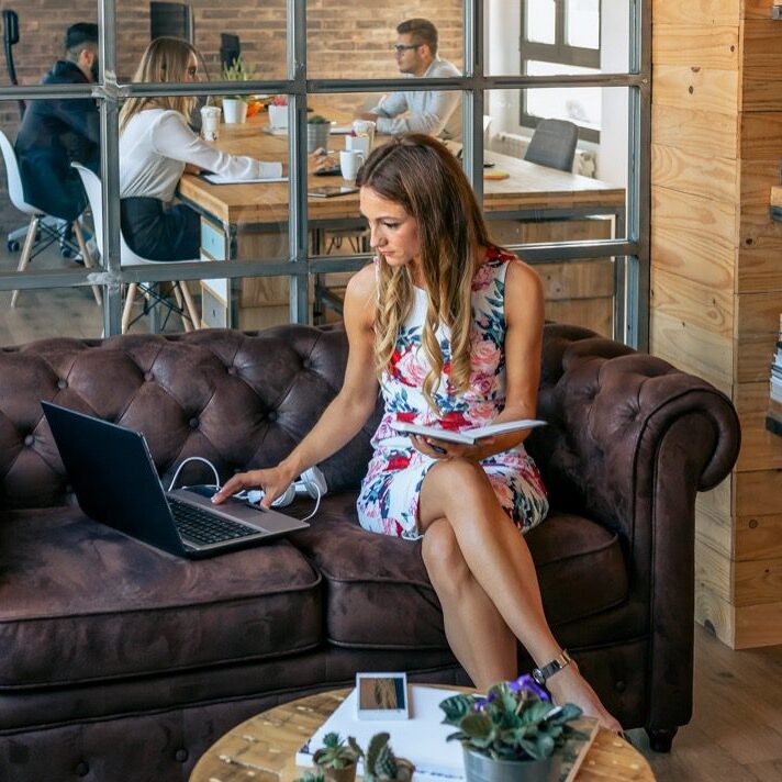 Businesswoman working with laptop sitting on the sofa in a coworking office